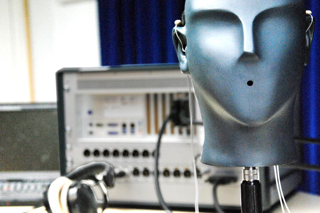 Messaufbau mit Kunstkopf, Hörgeräten und Hardware zur Echtzeitverarbeitung